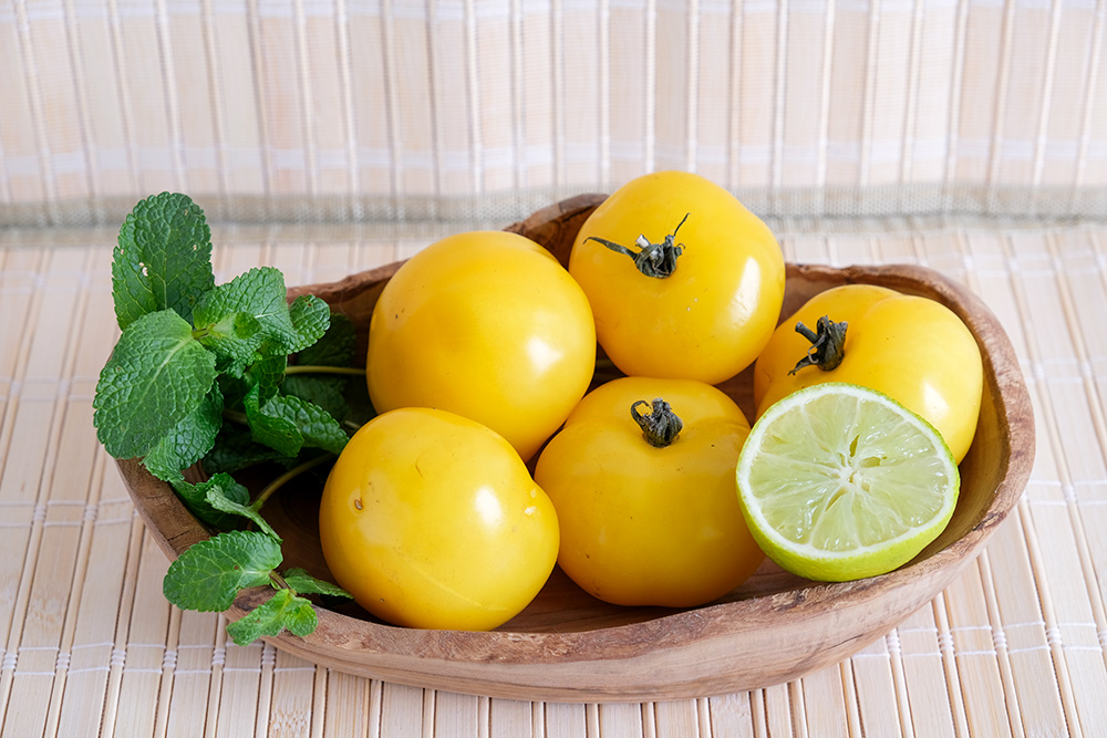 Gele tomaten in een schaal met verse munt en limoen. Foto: Kim van Dam