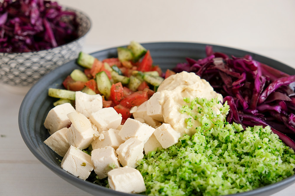 Buddha bowl op basis van broccolirijst met tomaat, rode kool en tofu, vegan, veganistisch, plantaardig